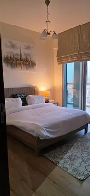 a bedroom with a large bed with white sheets at Cozy 2 BR apt Golf Tower Greens, stunning Golf views in Dubai
