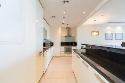 a kitchen with white cabinets and a black counter top at Royal Club By RVHR, Bonnington Residential Tower - JLT in Dubai