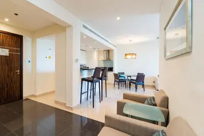 a living room and kitchen with chairs and a table at Royal Club By RVHR, Bonnington Residential Tower - JLT in Dubai