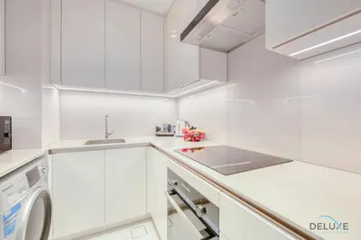 a white kitchen with a sink and a washing machine at Modern 1BR Oasis in Prime Location, Book Now by Deluxe Holiday Homes in Dubai