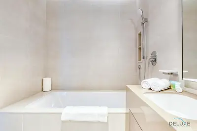 a white bathroom with a tub and a sink at Modern 1BR Oasis in Prime Location, Book Now by Deluxe Holiday Homes in Dubai