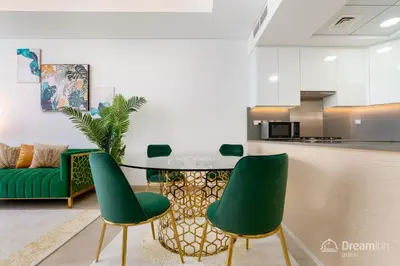 a living room with a table and green chairs at Dream Inn Apartments - Mina by Azizi in Dubai