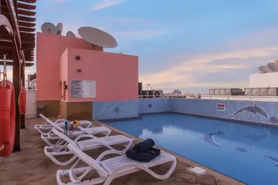 a pool on the roof of a building with lounge chairs at La Villa Najd Hotel Apartments in Dubai
