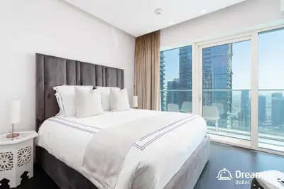 a bedroom with a large bed with a large window at Dream Inn - Damac Heights by Fendi in Dubai