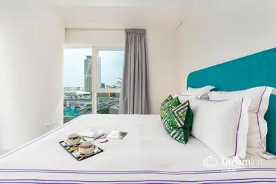 a bedroom with a white bed with a large window at Dream Inn - Damac Heights by Fendi in Dubai