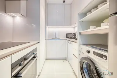 a white kitchen with a washer and dryer at Captivating 1BR at The Address Residences in JBR by Deluxe Holiday Homes in Dubai