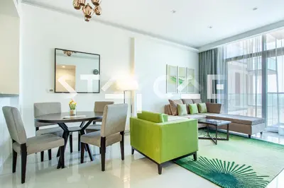 a living room with a table and a green chair at Staycae Holiday Homes - Celestia in Dubai