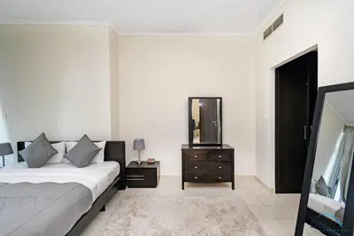 a bedroom with a bed and a mirror and a dresser at Steps Away From the Beach & Entertainment Hubs 1BR Unit, Torch Tower, Dubai Marina by Deluxe Holiday Homes in Dubai