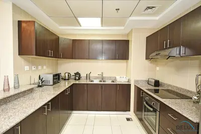 a large kitchen with wooden cabinets and a sink at Steps Away From the Beach & Entertainment Hubs 1BR Unit, Torch Tower, Dubai Marina by Deluxe Holiday Homes in Dubai