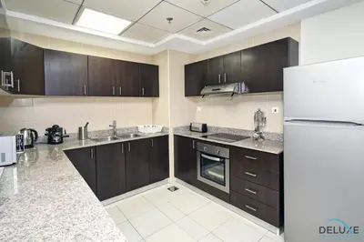a kitchen with wooden cabinets and a white refrigerator at Steps Away From the Beach & Entertainment Hubs 1BR Unit, Torch Tower, Dubai Marina by Deluxe Holiday Homes in Dubai