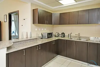 a large kitchen with wooden cabinets and a sink at Steps Away From the Beach & Entertainment Hubs 1BR Unit, Torch Tower, Dubai Marina by Deluxe Holiday Homes in Dubai