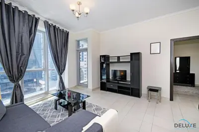 a living room with a couch and a tv at Steps Away From the Beach & Entertainment Hubs 1BR Unit, Torch Tower, Dubai Marina by Deluxe Holiday Homes in Dubai