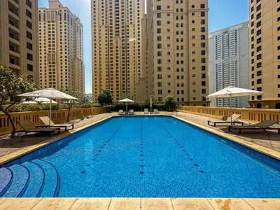 a swimming pool with chairs and umbrellas in a city at HiGuests - Artistic Waterfront Apt, Perfect for Beach Lovers in Dubai