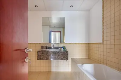a bathroom with a tub and a sink and a mirror at Frank Porter - Murjan 6 in Dubai