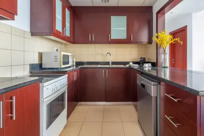 a kitchen with brown cabinets and a sink and a microwave at Frank Porter - Murjan 6 in Dubai