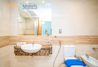 a bathroom with a sink and a toilet and a mirror at New Arabian Trident Waterfront 3 BR plus maid in Dubai