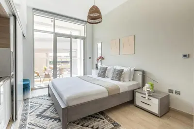a white bedroom with a large bed and a balcony at Frank Porter - Studio One in Dubai