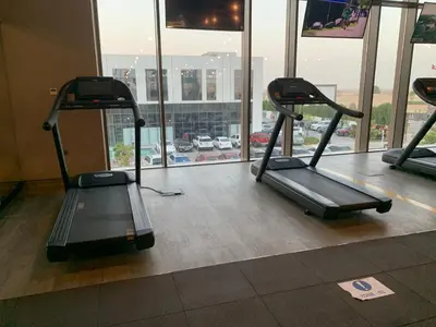 a gym with two treadmills in front of a window at Delightful 3BR Townhouse at DAMAC Hills 2 Dubailand by Deluxe Holiday Homes in Dubai