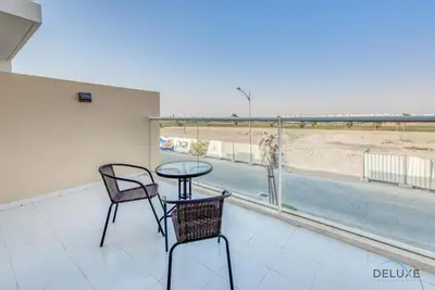a balcony with a table and two chairs and a pool at Delightful 3BR Townhouse at DAMAC Hills 2 Dubailand by Deluxe Holiday Homes in Dubai