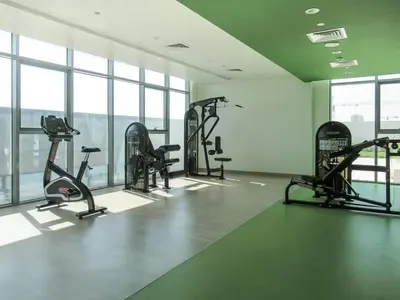 a gym with several tread machines in a room with windows at Frank Porter - Aura by Azizi in Dubai
