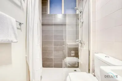 a white bathroom with a shower and a toilet at Opulent 3BR Townhouse at DAMAC Hills 2 Dubailand by Deluxe Holiday Homes in Dubai