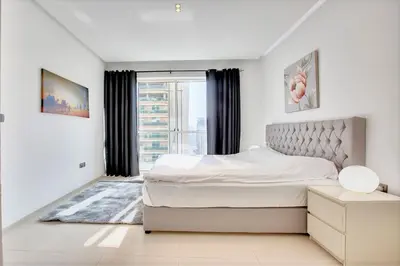a white bedroom with a bed and a window at 1 BD in West Avenue tower Dubai Marina in Dubai