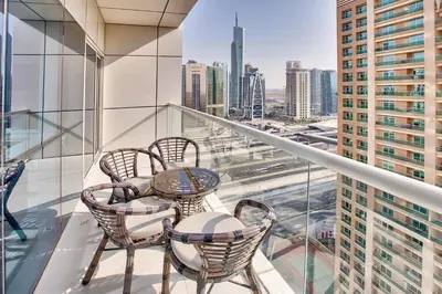 a balcony with tables and chairs and a view of the city at 1 BD in West Avenue tower Dubai Marina in Dubai