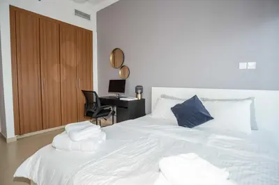 a bedroom with a bed with white sheets and a desk at WSuites - Big Terrace with Beautiful Marina View in Dubai