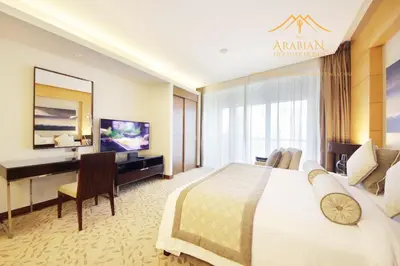 a hotel room with a large bed and a desk at New Arabian -Address Emaar Fashion Avenue in Dubai