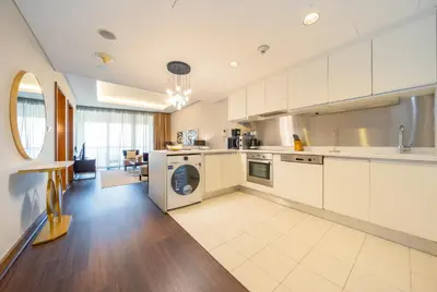 a kitchen with white cabinets and a washer and dryer at New Arabian -Address Emaar Fashion Avenue in Dubai