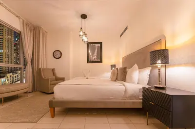 a bedroom with a large white bed and a chair at Spectacular Burj & Fountain View - Luxurious 3 Bedrooms & Maids room - The Residences in Dubai