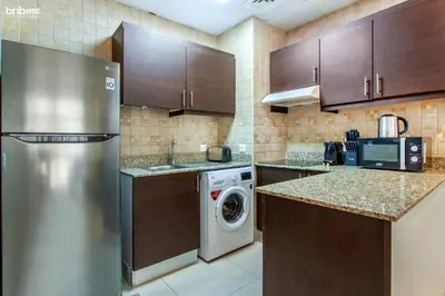 a kitchen with a refrigerator and a washing machine at bnbmehomes - La Fontana in Dubai