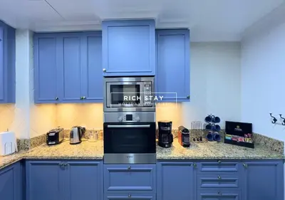 a kitchen with blue cabinets and a stove top oven at Spectacular 2BR in Souk Al Bahar, Downtown with Burj & Dubai Mall view by Rich Stay in Dubai