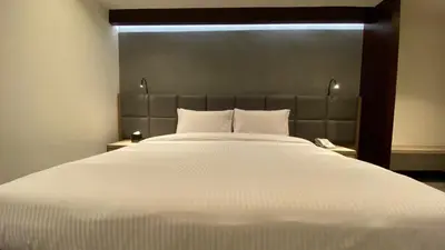 a bedroom with a large white bed with a headboard at SITARA HOTEL APARTMENT in Dubai