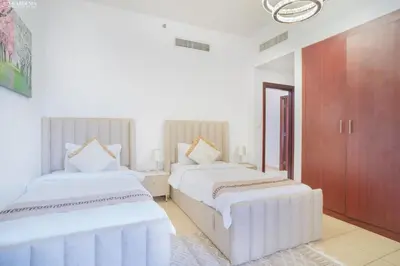two beds in a room with white walls at Gardenia Rimal Suites, Luxury Apartments in JBR with 2 min Walk to JBR beach in Dubai