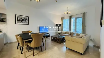 a living room with a table and a dining room at Canal View 2BR & Maid Room in KG Tower, Dubai Marina in Dubai