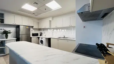 a kitchen with white cabinets and a counter top at Canal View 2BR & Maid Room in KG Tower, Dubai Marina in Dubai