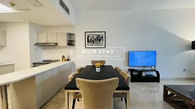 a kitchen and dining room with a table and a tv at Canal View 2BR & Maid Room in KG Tower, Dubai Marina in Dubai