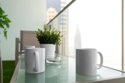 three white coffee mugs sitting on a glass table on a balcony at White Sage - Incredible Full Sea and Dubai Eye View in Marina in Dubai