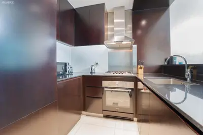 a kitchen with wooden cabinets and a stainless steel oven at Downtown Damac Distinction Full Burj View in Dubai