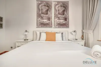 a bedroom with a large white bed with two pictures on the wall at Lively 1 BR at Al Nabat Shoreline 8 Palm Jumeirah by Deluxe Holiday Homes in Dubai