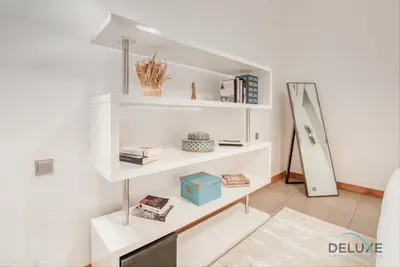 a living room with white shelves and a mirror at Lively 1 BR at Al Nabat Shoreline 8 Palm Jumeirah by Deluxe Holiday Homes in Dubai