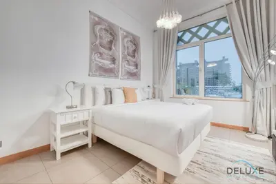a white bedroom with a large bed and a window at Lively 1 BR at Al Nabat Shoreline 8 Palm Jumeirah by Deluxe Holiday Homes in Dubai