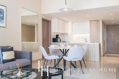 a kitchen and a living room with a table and chairs at LUX Contemporary Suite with Marina View 3 in Dubai