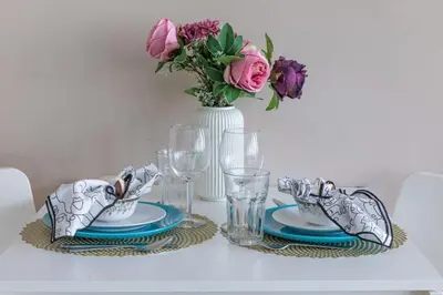 a table with plates and glasses and a vase with flowers at Frank Porter - Indigo Tower in Dubai