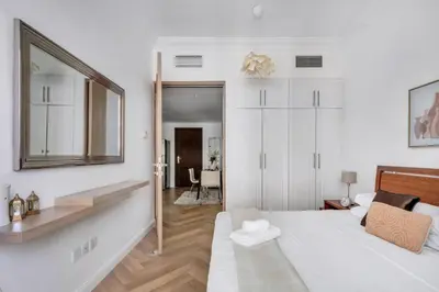 a white bedroom with a bed and a mirror at GuestReady - Marina Views | 1BR + Pool & Gym in Dubai