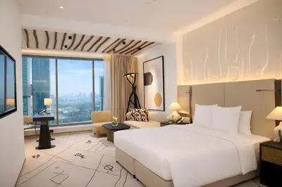 a bedroom with a large white bed and a large window at The H Dubai in Dubai