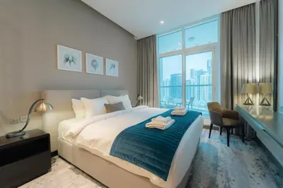a bedroom with a bed and a desk and a large window at AWS Holiday Homes - Panoramic Canal View in Dubai