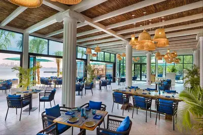 a dining room with tables and chairs and windows at Anantara World Islands Dubai Resort in Dubai