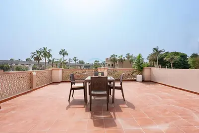 a patio with a table and chairs on a balcony at Luxury Beachfront Villa with Direct Beach Access, Next to Community Pool, Close to the Thrills of Aquaventure Waterpark, Canal Cove, Palm Jumeirah by Deluxe Holiday Homes in Dubai